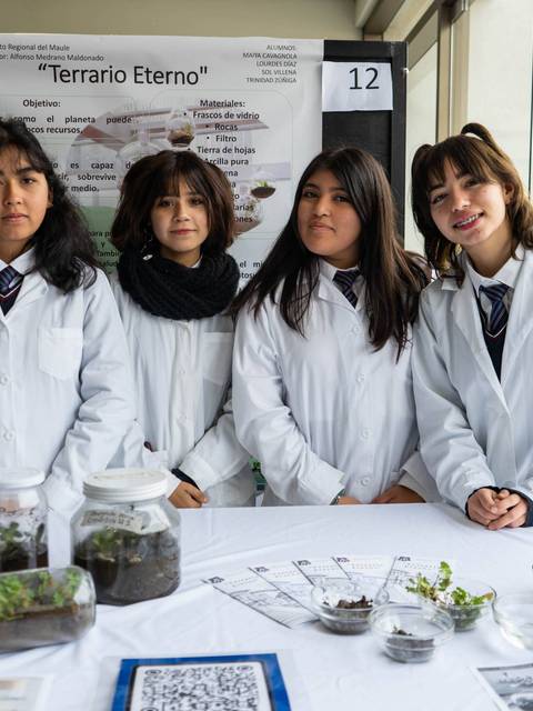 Estudiantes presentan un proyecto sobre un terrario en un evento educativo.