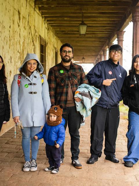 Un grupo de seis personas posando en un pasillo antiguo bajo una estructura de madera.