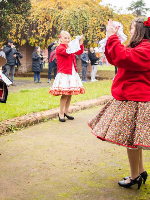 Un grupo de personas bailando en un evento tradicional al aire libre, con vestimenta típica y un público observando.