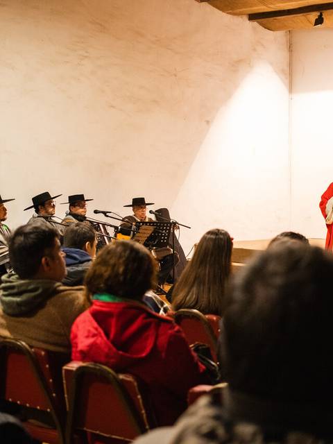 Una representación cultural con músicos y un presentador en un evento comunitario.