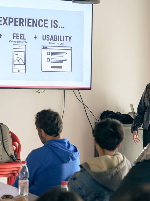 Una presentadora explica el concepto de experiencia de usuario a un grupo de personas en un evento.