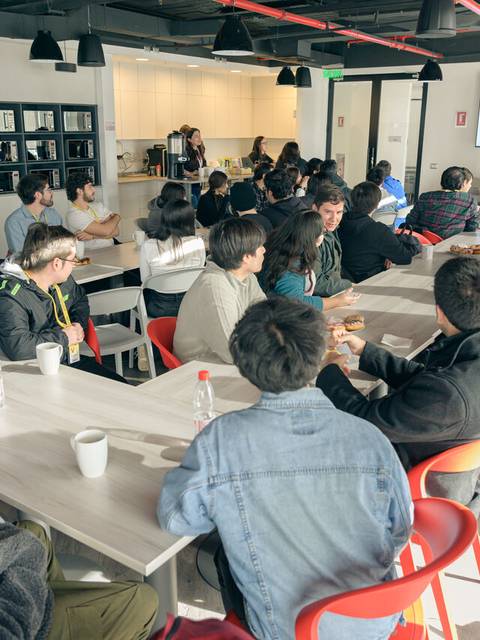 Un grupo de personas sentadas en una sala de reuniones mientras asisten a una presentación.