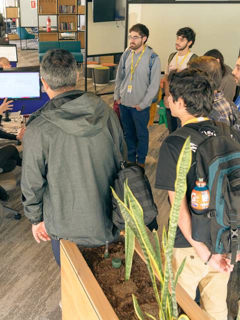 Un grupo de personas observa a una mujer que está explicando algo en una oficina moderna.