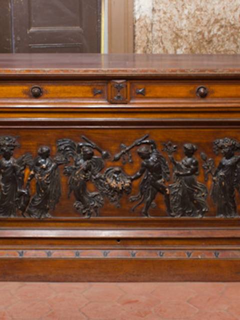 Mueble de madera tallada con detalles ornamentales y figuras en relieve.