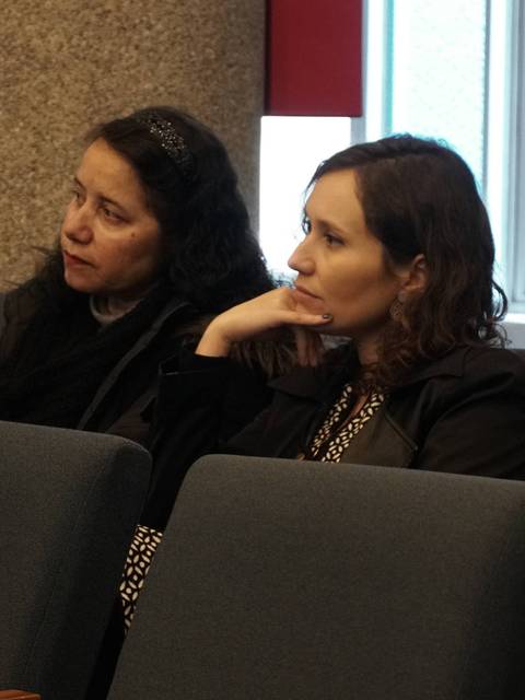 Dos mujeres sentadas en un salón, mostrando atención en una conversación.