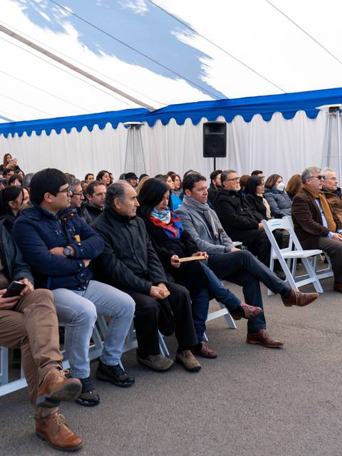 Una multitud de personas sentadas en un evento bajo una carpa blanca.