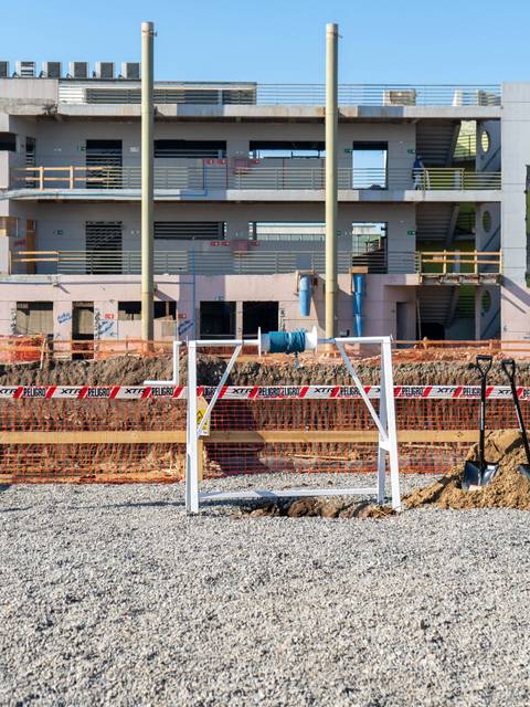 Una construcción en proceso con una portería de fútbol y banderas en el frente.