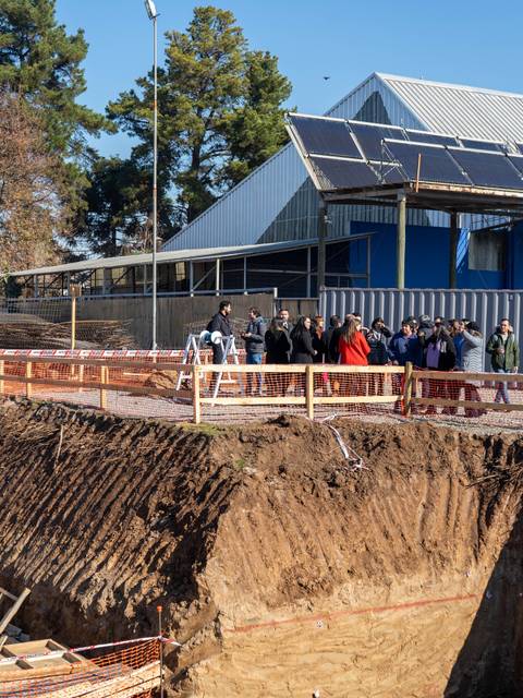 Un grupo de personas camina junto a una construcción con paneles solares en un día soleado.