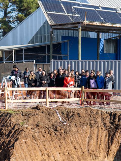 Un grupo de personas se encuentra frente a una obra, al borde de un gran hoyo en el terreno.