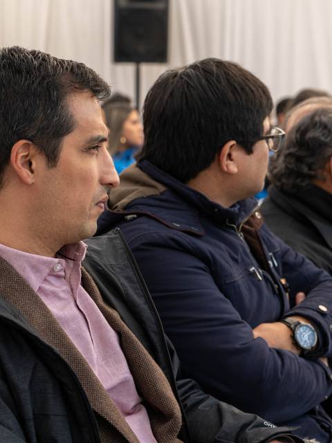 Un grupo de personas sentadas en un evento, mirando hacia el frente.