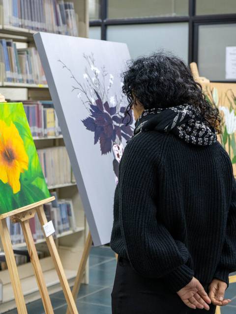 Una persona observa pinturas en una galería dentro de una biblioteca.