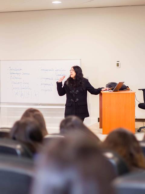 Una profesora da una charla sobre Jean Piaget frente a un grupo de estudiantes en un aula.