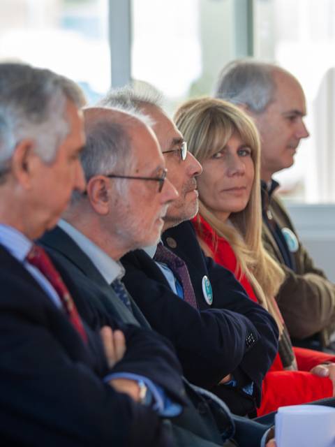 Un grupo de personas sentadas en una reunión, mostrando expresiones serias.