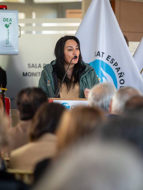 Una mujer está dando un discurso en un evento frente a un público atento.