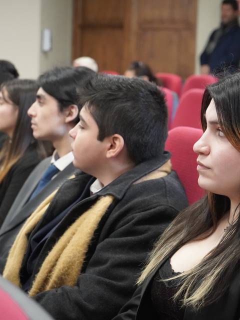 Un grupo de jóvenes sentados en filas, atentos durante un evento.