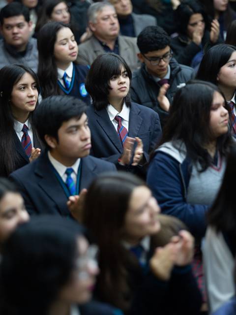 Un grupo de estudiantes aplaudiendo durante un evento en un auditorio.