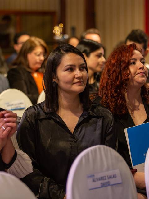 Un grupo de personas sentadas en un evento, escuchando atentamente.