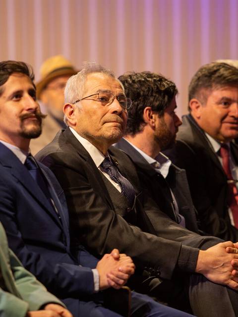 Una audiencia atenta observa un evento formal.