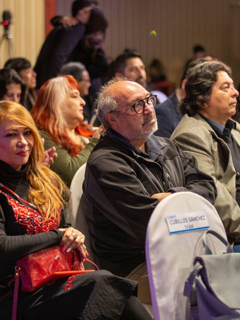 Un grupo de personas sentadas en un evento, prestando atención al orador.