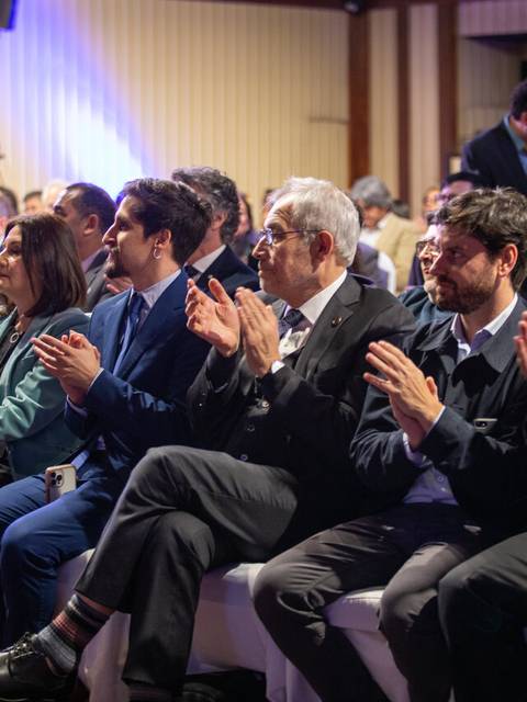 Un grupo de personas aplaudiendo en un evento formal.