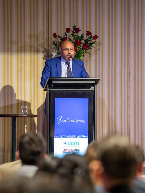 Un hombre vestido de traje habla en un podio durante una ceremonia de graduación.