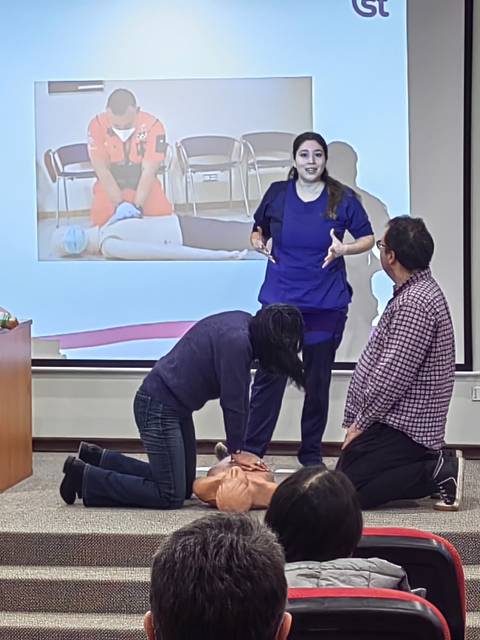 Una presentación educativa sobre reanimación cardiopulmonar (RCP) con varios participantes practicando la técnica.