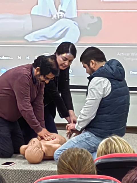 Un grupo de personas está realizando una práctica de resucitación cardiopulmonar (RCP) en un maniquí durante un taller.