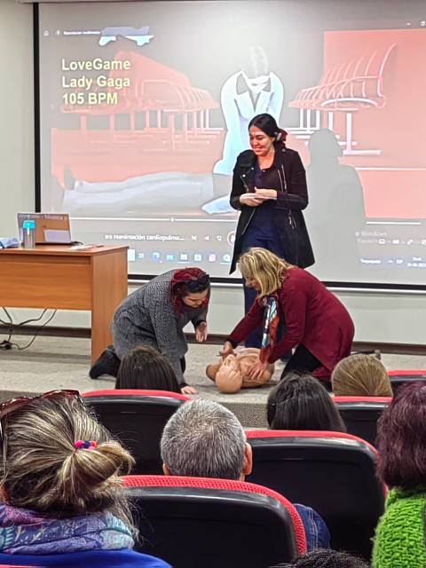 Una presentación educativa sobre reanimación cardiopulmonar en un aula con asistentes observando.