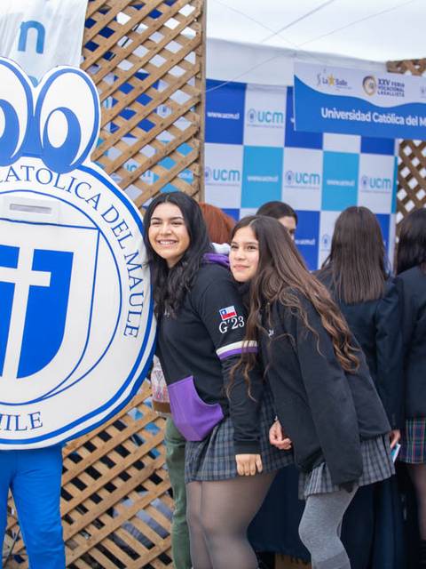 Imagen de un evento en la Universidad Católica del Maule con estudiantes posando junto a una figura del logo universitario.