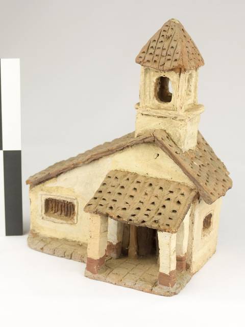 Una réplica de una pequeña iglesia con campanario en colores terrosos.