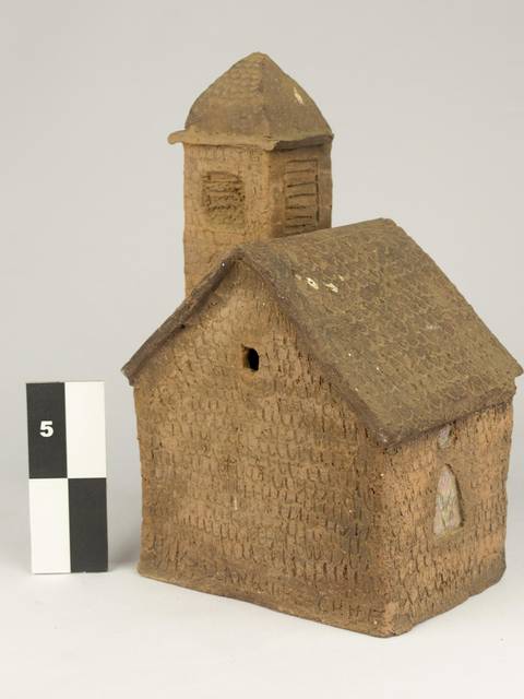La imagen muestra una pequeña construcción en miniatura, similar a una iglesia, hecha de un material que parece barro.