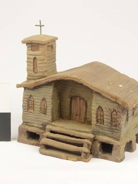 Una maqueta de una iglesia con un campanario y una cruz en el techo.