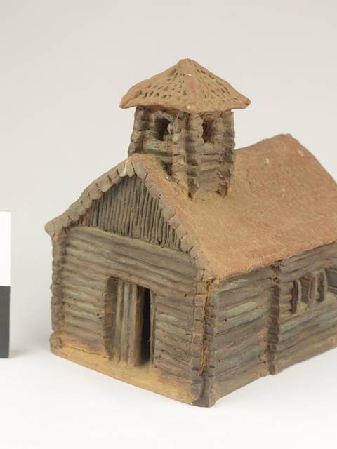 Una maqueta de una pequeña iglesia de madera con un campanario.