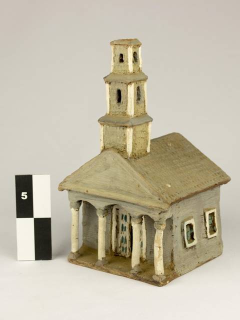 Una pequeña maqueta de una iglesia con un campanario y columnas en la fachada.