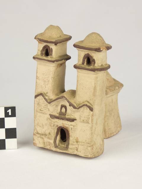 Una figura de una iglesia en cerámica con dos torres y un diseño simple.