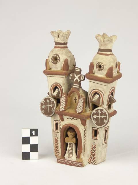 Una figura de cerámica que representa una iglesia con torres y decoraciones características.