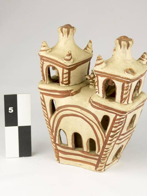 Se trata de una figura decorativa en forma de edificio con torres, hecha de cerámica.