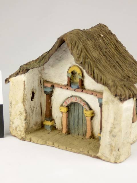 Una maqueta de una casa de estilo rústico con techo de paja.