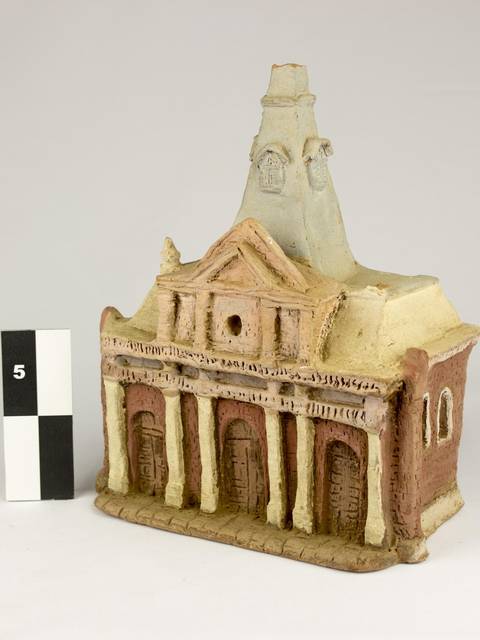 Una escultura que representa un edificio con detalles arquitectónicos y un color terroso.