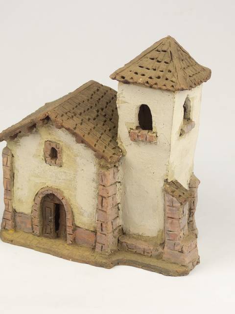 Una pequeña casa de cerámica con un campanario y un tejado de tejas.