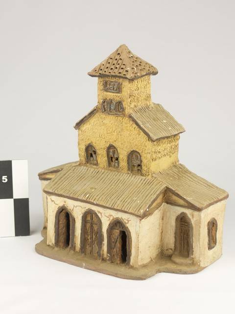 La imagen muestra una maqueta de una construcción con torres y un tejado a dos aguas.