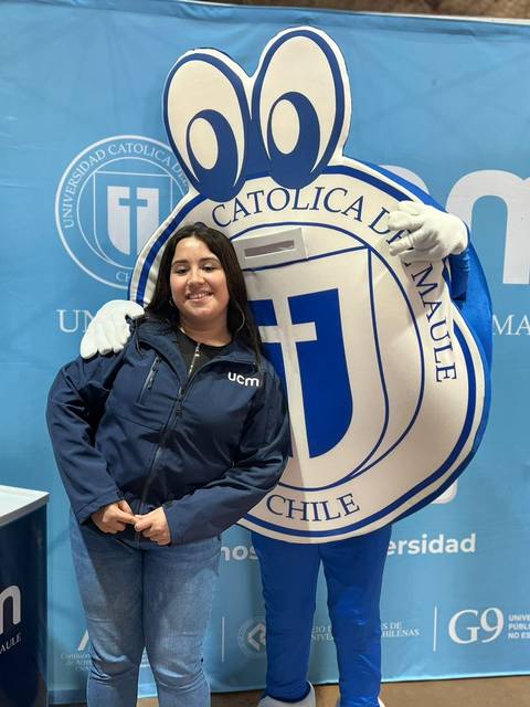 Una mujer posa junto a una mascota en un evento universitario.