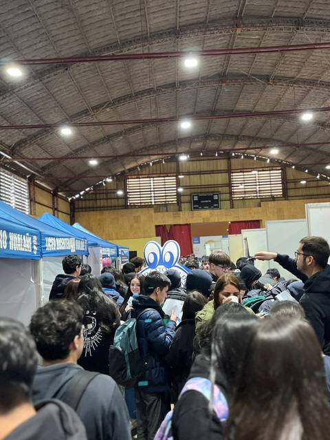 Multitud de estudiantes en un evento escolar dentro de un recinto cerrado.