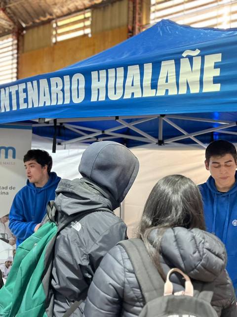 Un grupo de personas interactúa en un stand del Liceo Bicentenario Hualañe durante un evento.