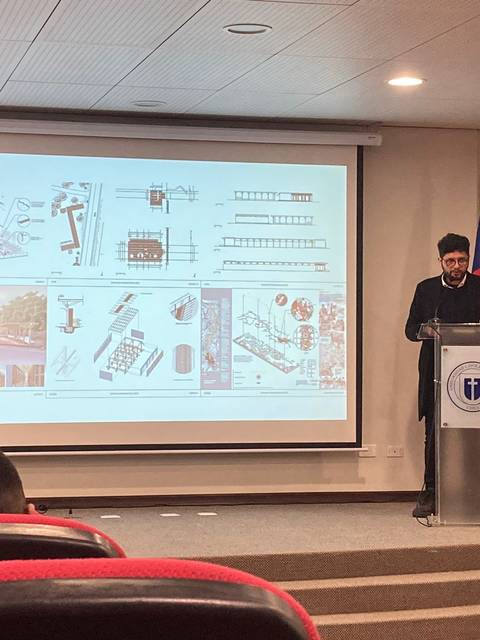 Un presentador expone un proyecto frente a una audiencia mientras se proyectan gráficos detrás de él.