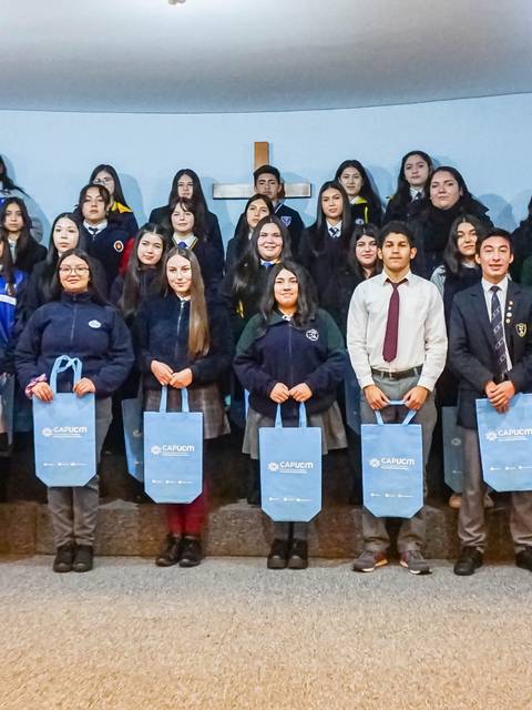Un grupo de estudiantes posesiona sonriente en una ceremonia de entrega de obsequios.