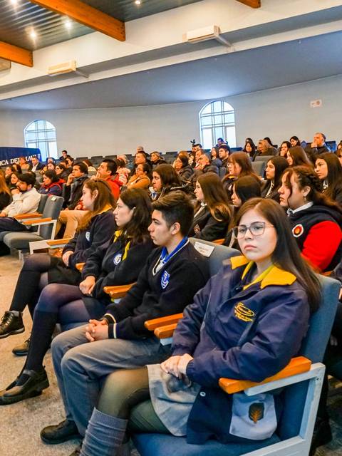 Un grupo de jóvenes y adultos asisten a un evento en un auditorio.