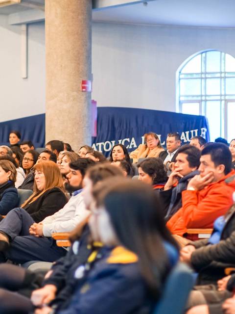 Un grupo de personas sentadas en un auditorio asistiendo a una presentación.