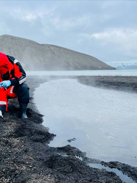 Un investigador toma muestras en un entorno volcánico cerca del agua.