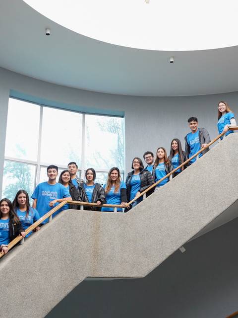 Un grupo de personas posa en una escalera con camisetas azules.